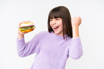 Little caucasian girl holding a burger over isolated background celebrating a victory