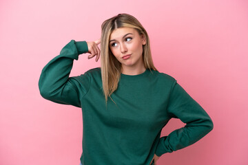 Young caucasian woman isolated on pink background making the gesture of madness putting finger on...