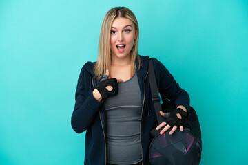 Young sport woman with sport bag isolated on blue background with surprise facial expression