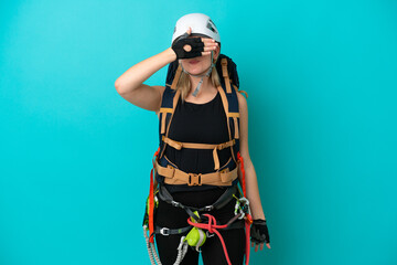 Young caucasian rock climber woman isolated on blue background covering eyes by hands. Do not want to see something