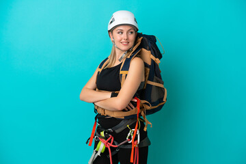 Young caucasian rock climber woman isolated on blue background with arms crossed and happy
