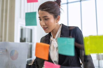 Employee meeting at office and use post it notes to share idea brainstorming stick on glass wall