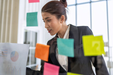 Employee meeting at office and use post it notes to share idea brainstorming stick on glass wall
