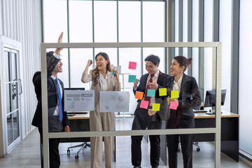 Employee meeting at office and use post it notes to share idea brainstorming stick on glass wall