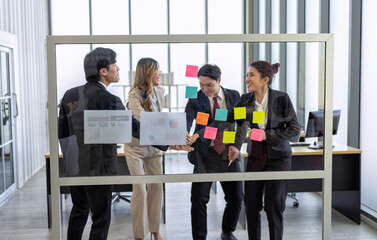Employee meeting at office and use post it notes to share idea brainstorming stick on glass wall