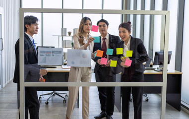 Employee meeting at office and use post it notes to share idea brainstorming stick on glass wall