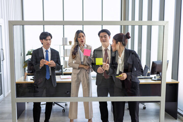 Employee meeting at office and use post it notes to share idea brainstorming stick on glass wall