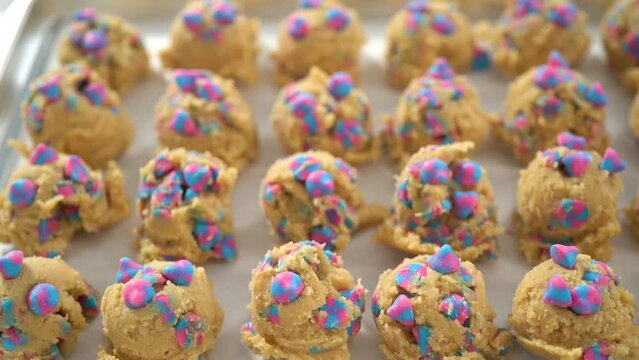 Chilled cookie dough scoops on the baking sheet to bake unicorn chocolate chip cookies.