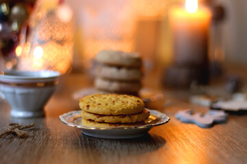 Two types of cookies, cups of tea or coffee, various Christmas decorations and lit candles. Cozy...