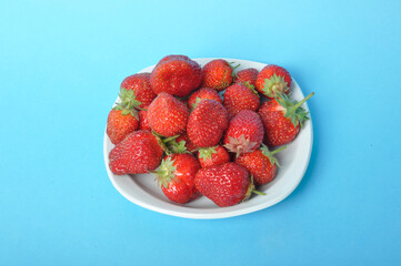 Strawberries on a plate on a blue background