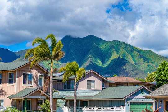 Close-up of residential homes in the town of Kahului, painted in pastel colors with the dramatic West Maui Mountains in the background; Maui, Hawaii, United States of America