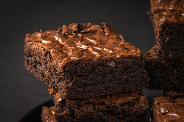 Close up on a stack of rich chocolate brownies on a dark plate.