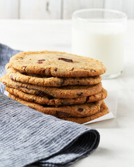 Chocolate chip cookies stacked beside a glass of milk.