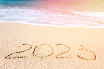Fototapeta na wymiar Top view of 2023 numbers written on the sand of coastline