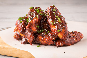Glazed chicken wings garnished with sesame seeds and green onions.