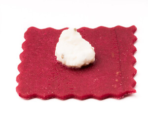 Beetroot ravioli pasta with ricotta cheese on white.