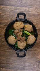 Delicious meatballs in wok pan on wooden background. Indonesian Food