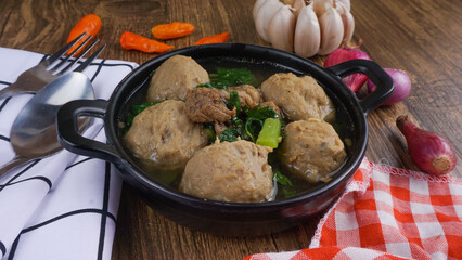 Delicious meatballs in wok pan on wooden background. Indonesian Food