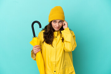 Young caucasian man holding an umbrella isolated on blue background frustrated and covering ears