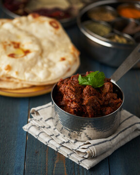 A rustic bowl of richly spiced Indian chicken tikka masala with naan bread, ideal for a stock photo with a focus on traditional cuisine.