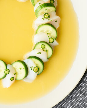 Scallop crudo with cucumber in bright yellow citrus sauce