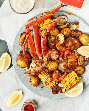 Large seafood boil on galvanized metal plate with crab, potatoes, shrimp, corn, clams
