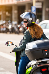 Fototapeta na wymiar Red-haired woman riding a motorcycle on a city street
