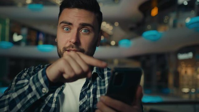 Excited hispanic businessman winner shopper pointing on phone screen male user happy man overjoyed with mobile online bet bid app win business profit look at cellphone celebrate victory read good news