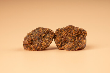 brown broken pieces of hashish on a beige background - obrazy, fototapety, plakaty