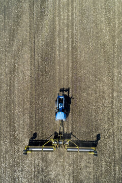 Aerial view of a tractor pulling rollers to flatten a field; Acme, Alberta, Canada