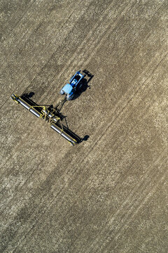Aerial view of a tractor pulling rollers to flatten a field; Acme, Alberta, Canada