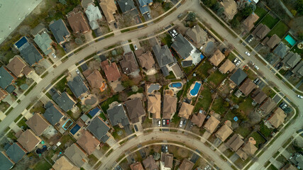 An aerial drone shot of roads, houses, backyards & swimming pools in the suburbs