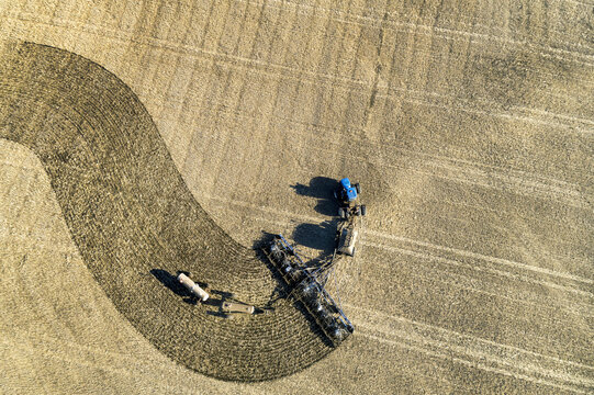 Aerial view of a tractor pulling an air seeder, seeding a field; Beiseker, Alberta, Canada