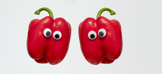 Two red Bell Peppers with googly eyes isolated on a white background