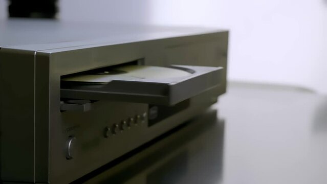 Close-up woman's hand pulls out an old CD from a dvd player.