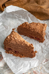 Napoleon cake with custard is decorated with cherries and grated chocolate on table.