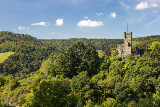 Stone castle turret on top of rolling treed hills with blue sky and clouds; Serrig, Germany