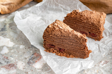 Napoleon cake with custard is decorated with cherries and grated chocolate on table.