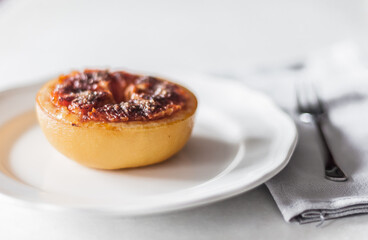 A baked grapefruit with caramel on a white plate.