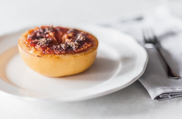 A baked grapefruit with caramel on a white plate.