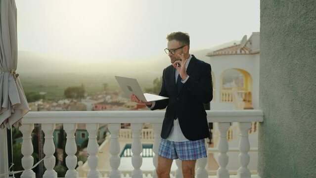 Man in a jacket and underwear negotiates at home on the terrace of a villa
