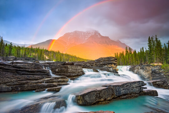 Double rainbow shining over a rugged waterfall and the Rocky Mountains, Jasper National Park; Alberta, Canada