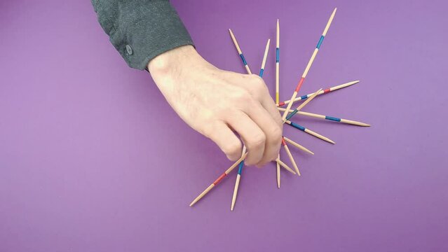Mikado Shanghai Board Game With Wooden Sticks. Game example, moved a stick. The hand of an elderly man can be seen.