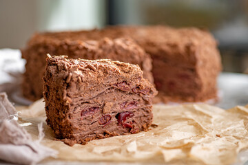 Napoleon cake with custard is decorated with cherries and grated chocolate on table.