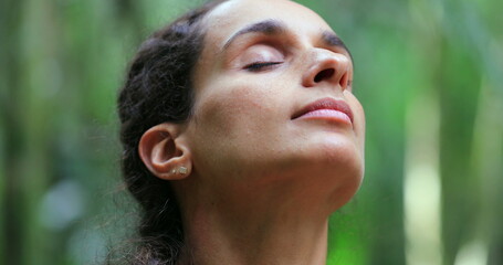 Woman with eyes closed taking a deep breath in meditation in nature