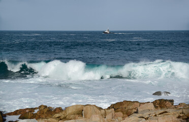 Blue sea with white surf and a ship on the waves