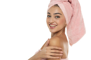 A pretty smiling young woman with towel on her head posing on a white background