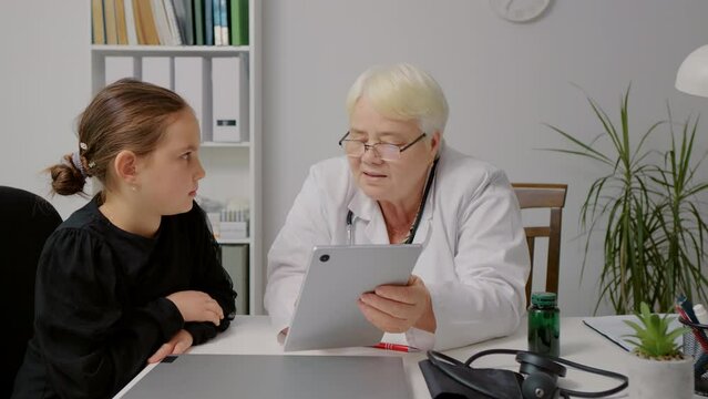 Experinced psychologist having an online test on device with a school girl. Doctor appoinment with young lady.