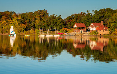 Jamaica Pond view across the water of the boat house and music building. Boats are in the water. A...