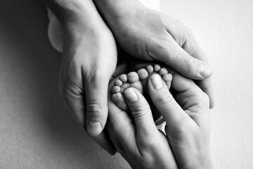Children's legs in the hands of mother, father. Feet of a newborn close-up. 